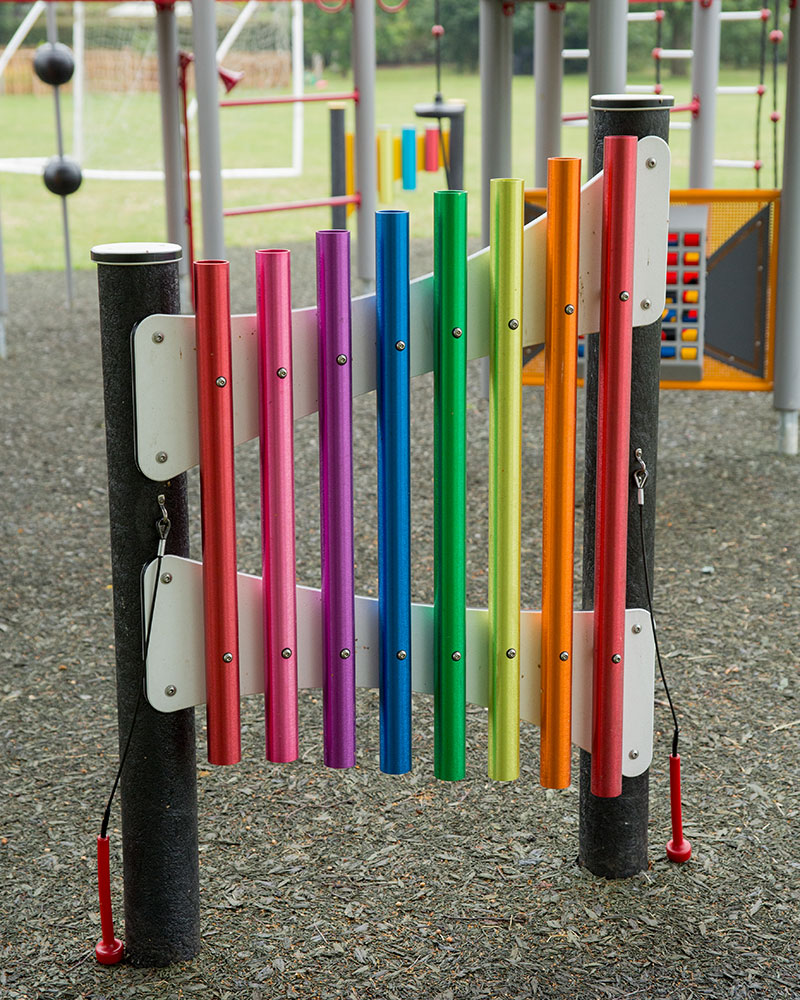 Musical play panels at a playground which are colorful bars for making noises on.